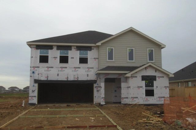 Exterior of a two-story new construction home in Manvel, Texas, with house wrap partially installed during the construction phase.