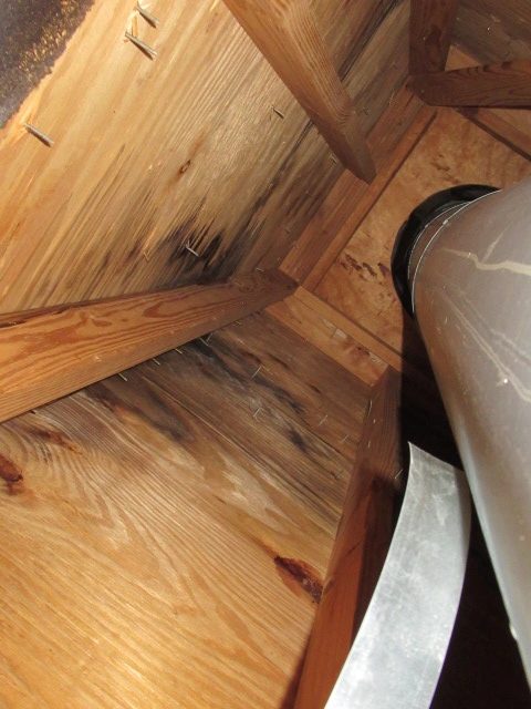 Chimney flue and surrounding roof framing viewed from inside the attic.