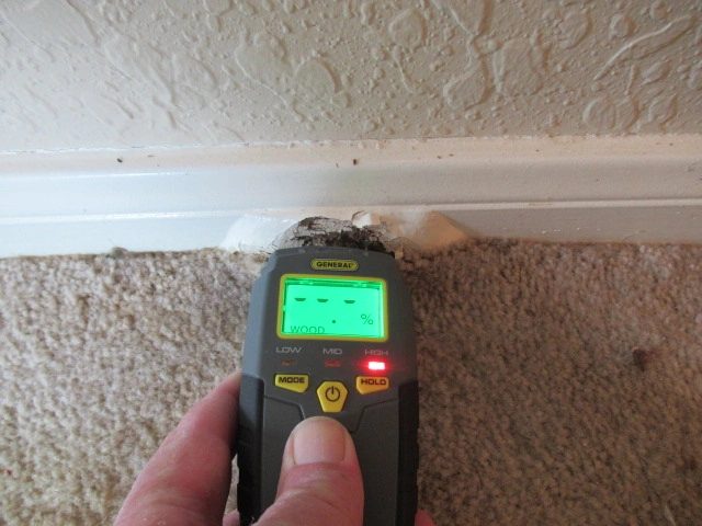 The baseboard under the window was swollen from water penetration and showed high moisture reading when checked with the moisture detector during the inspection.