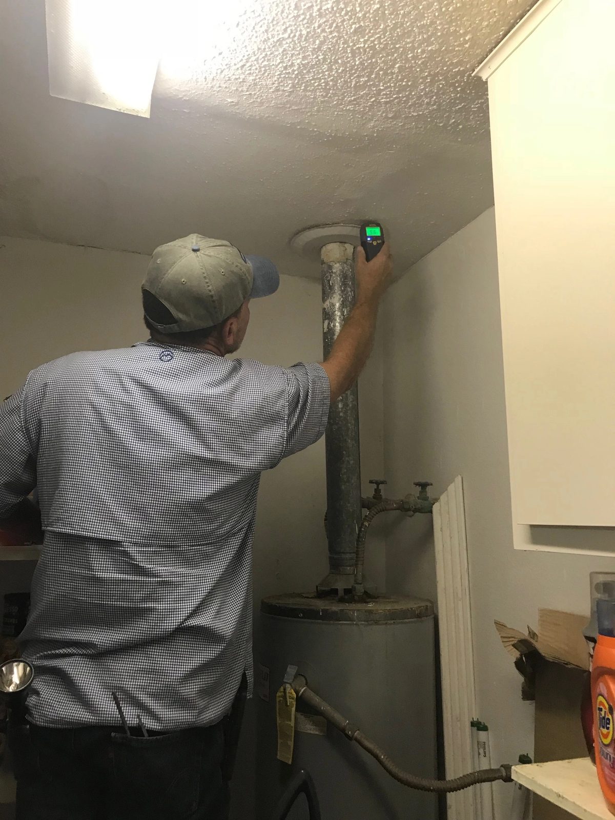 Brad Leland using a moisture meter near a water heater flue to investigate a possible moisture concern