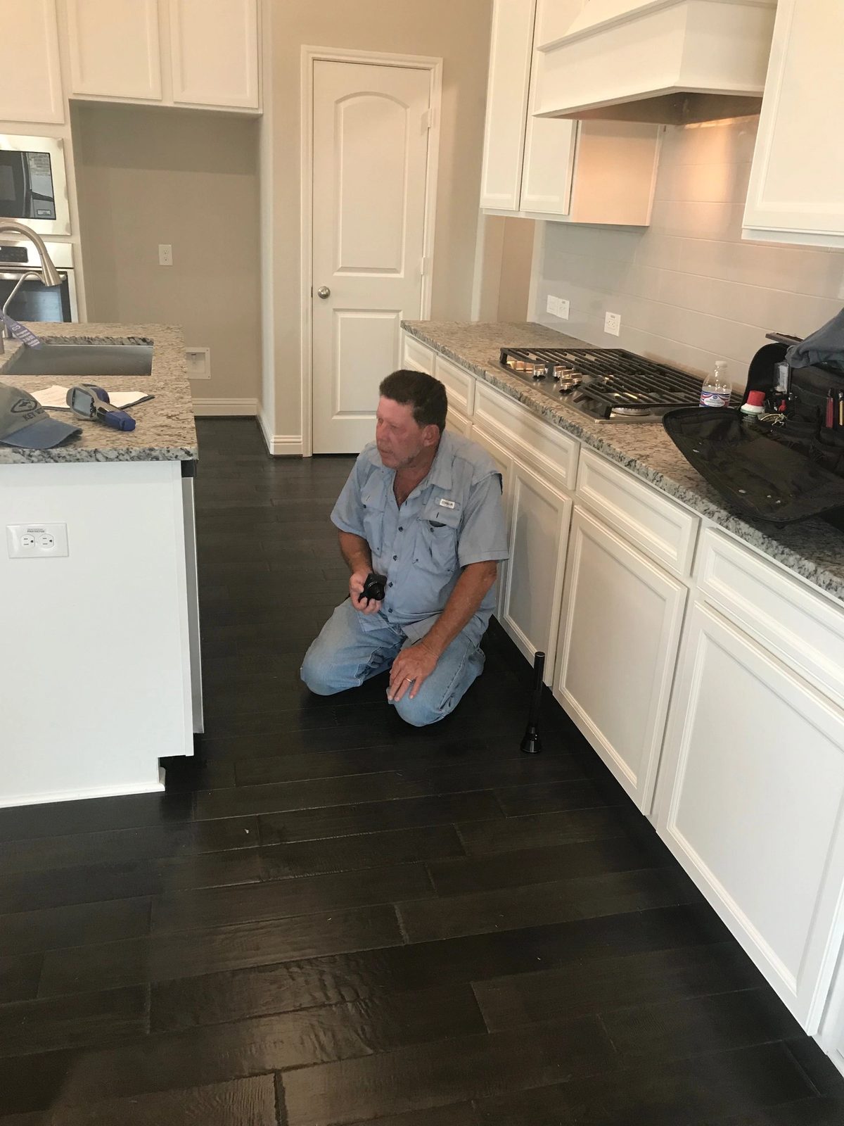 Brad checking kitchen plumbing and appliances during a new-home final inspection.