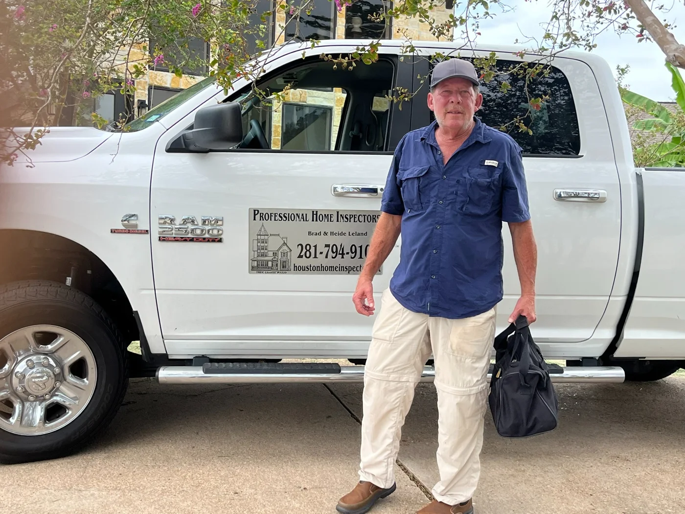Brad Leland beside his inspection truck holding his inspection bag