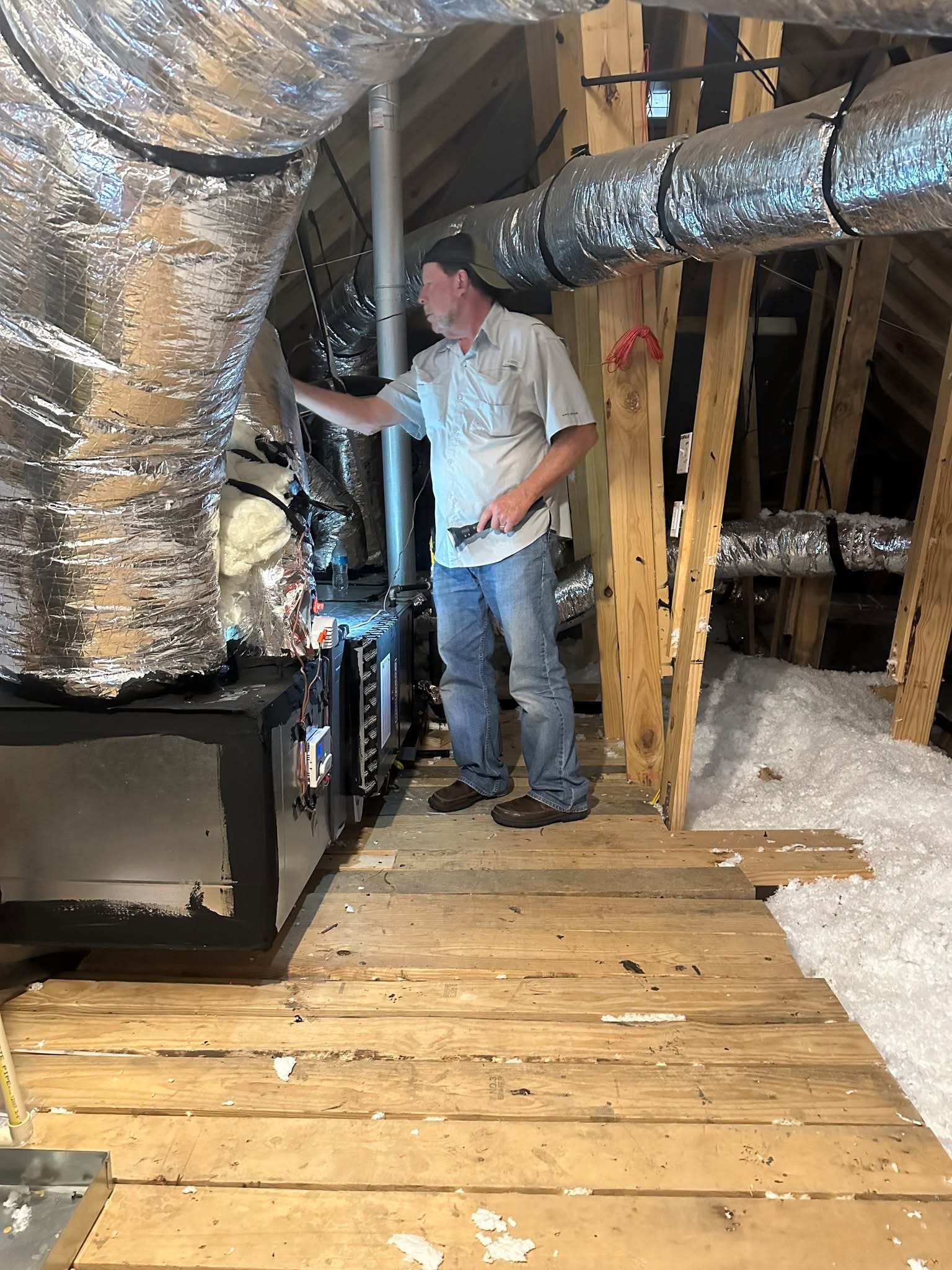 Brad Leland examining accessible heating and cooling equipment in an attic