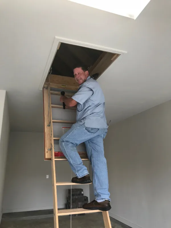 Brad Leland on an attic ladder during a home inspection